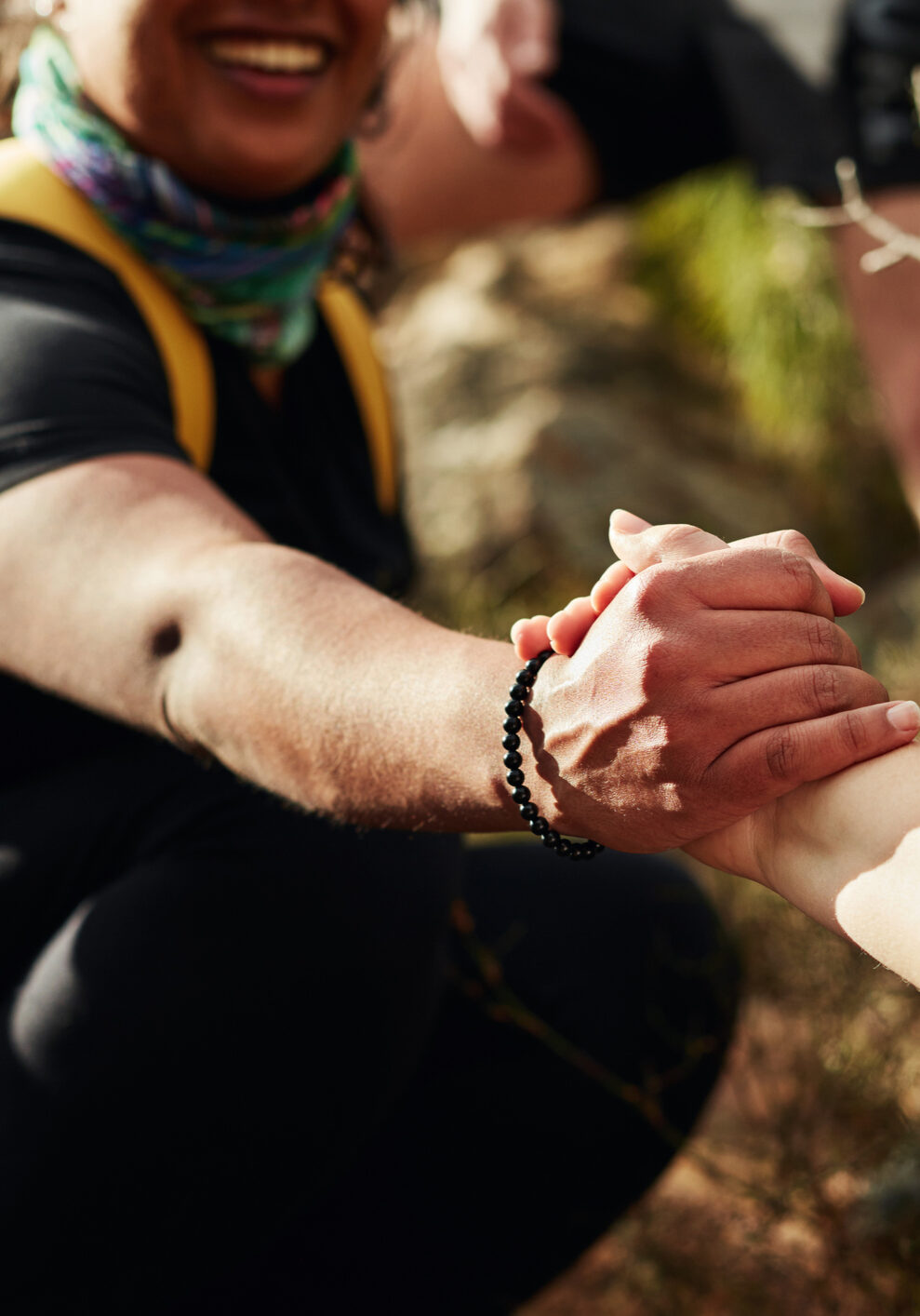 Cropped shot of two young women reaching for each other's hands on a hiking trail